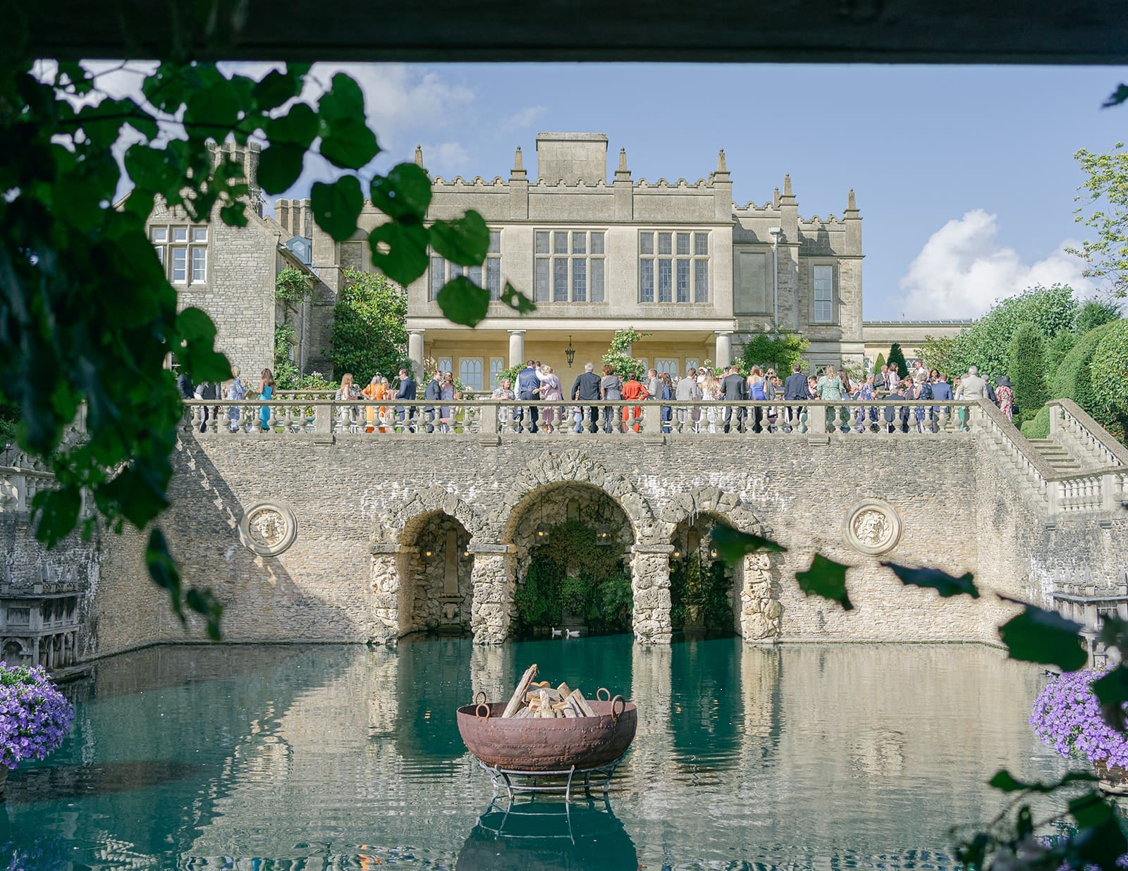Euridge Manor wedding photography by Becky Tranter -- guests gathered on the terrace above the lily pond during drinks reception, Chippenham Wiltshire